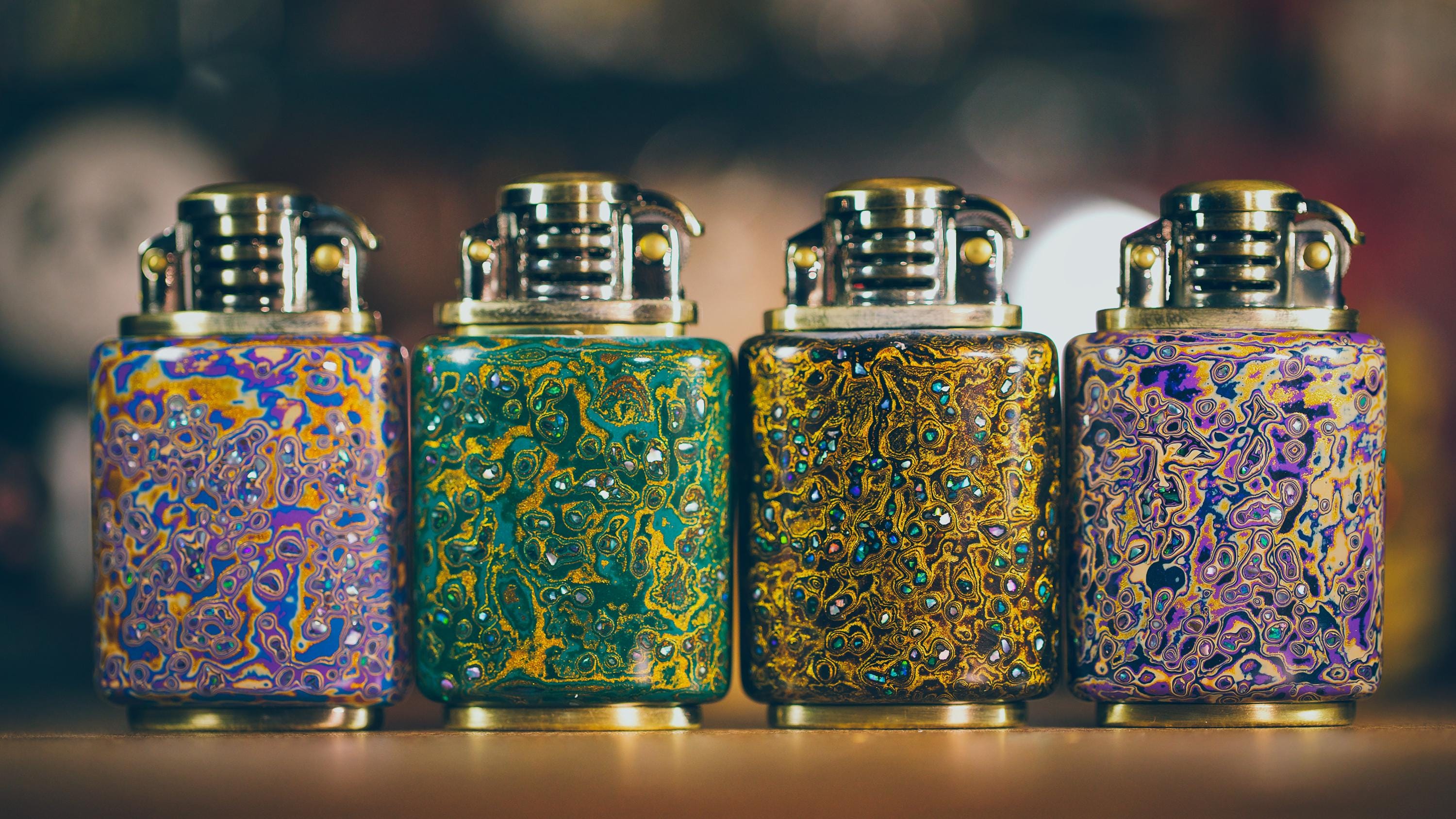 Four ornate glass lighters with intricate patterns 
