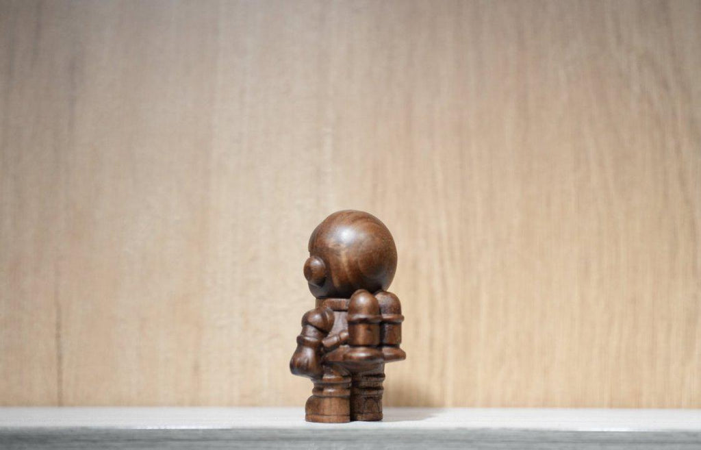 Wooden sculpture of a figure on a neutral background