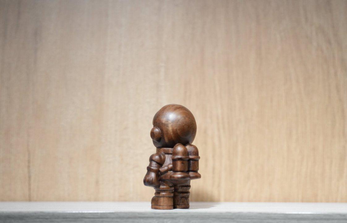 Wooden sculpture of a figure on a neutral background