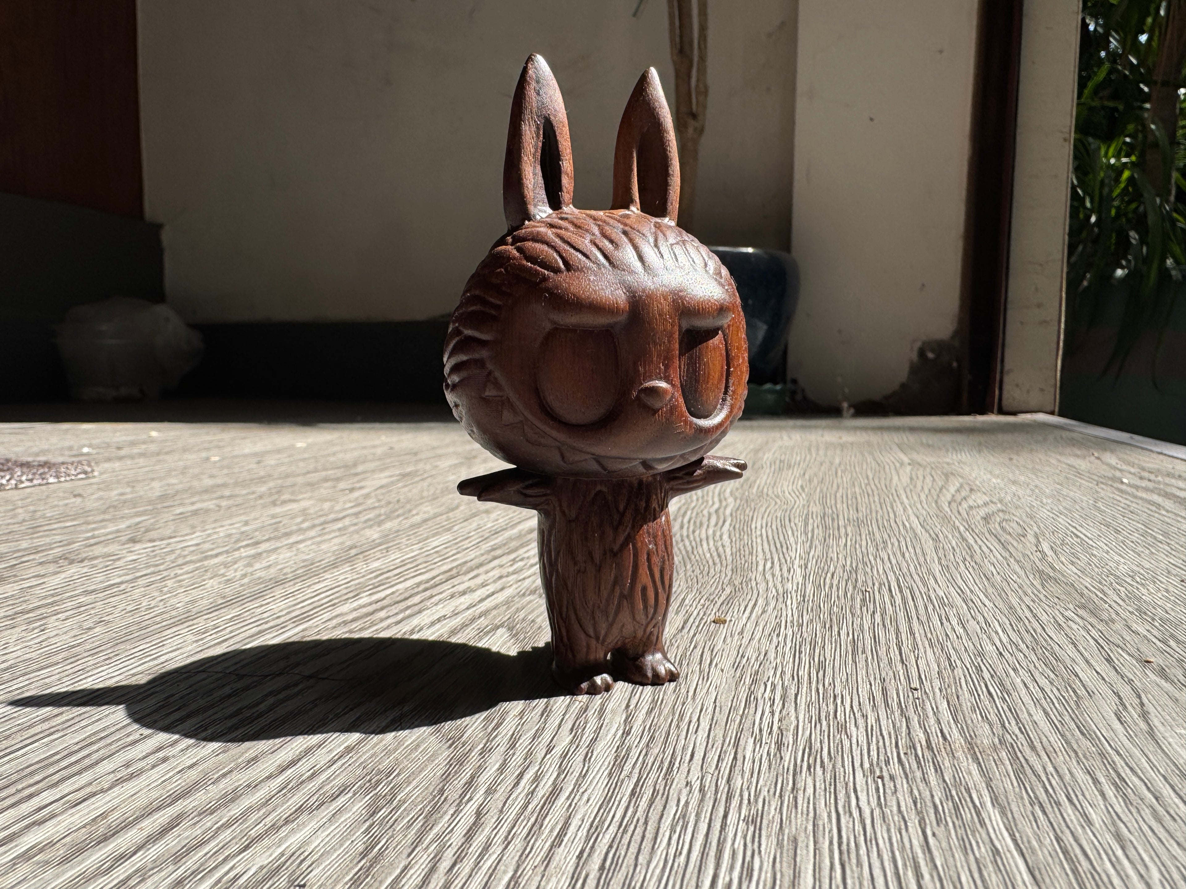 Wooden rabbit figurine on a textured surface with a neutral background