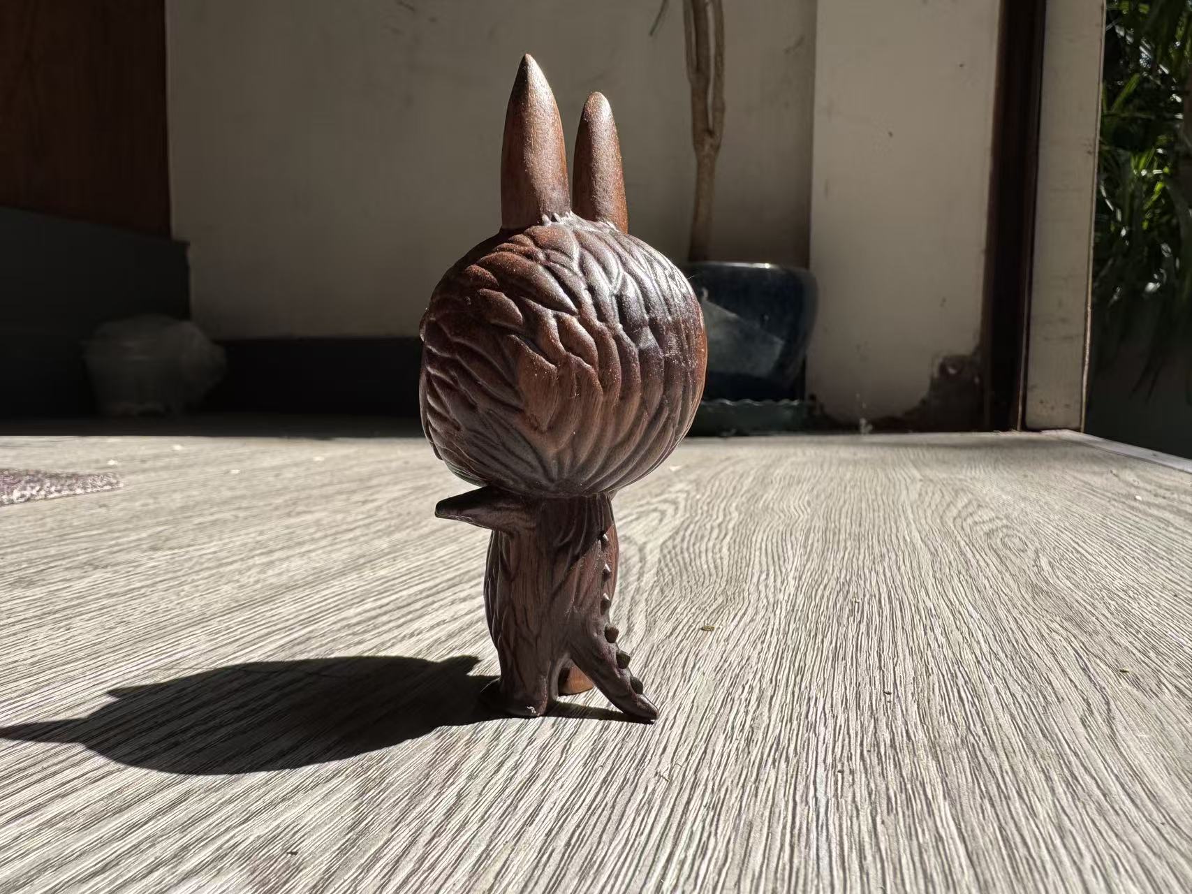 Wooden rabbit figurine on a textured surface with a neutral background