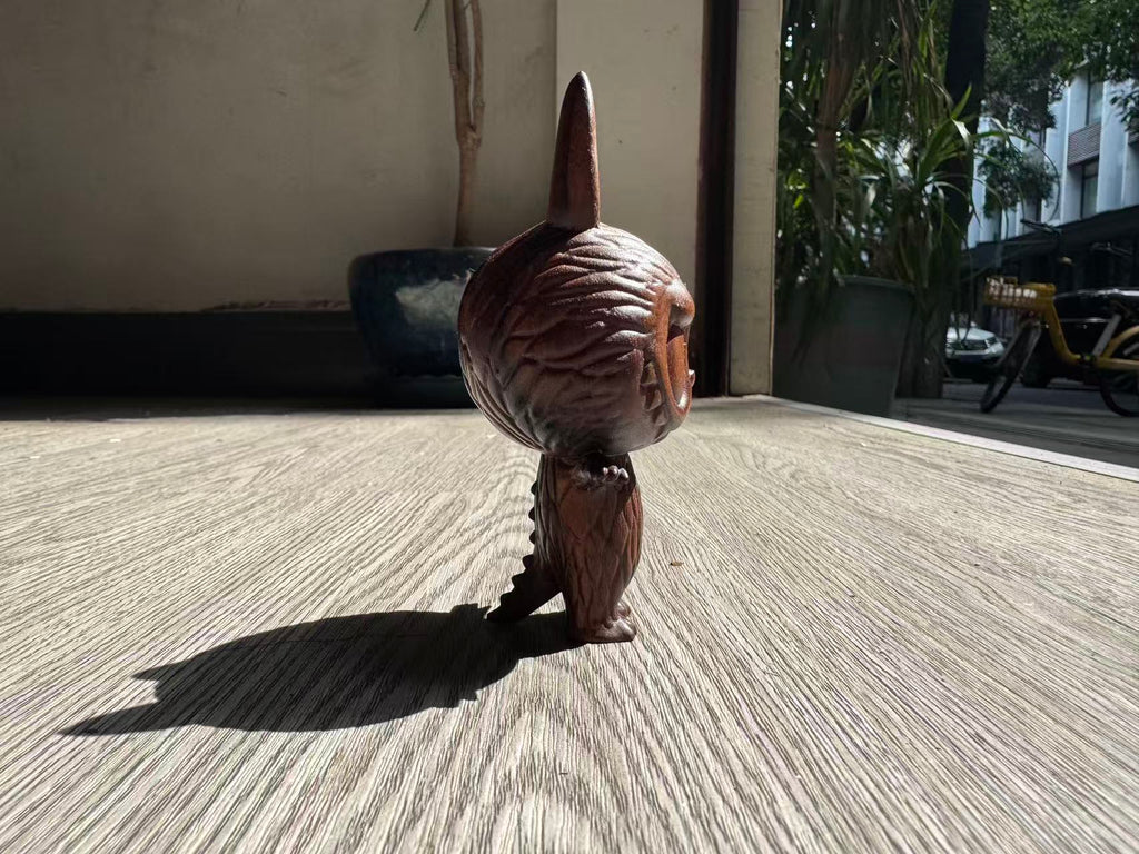 Small brown dog with a large, textured object on its head standing on a concrete surface.