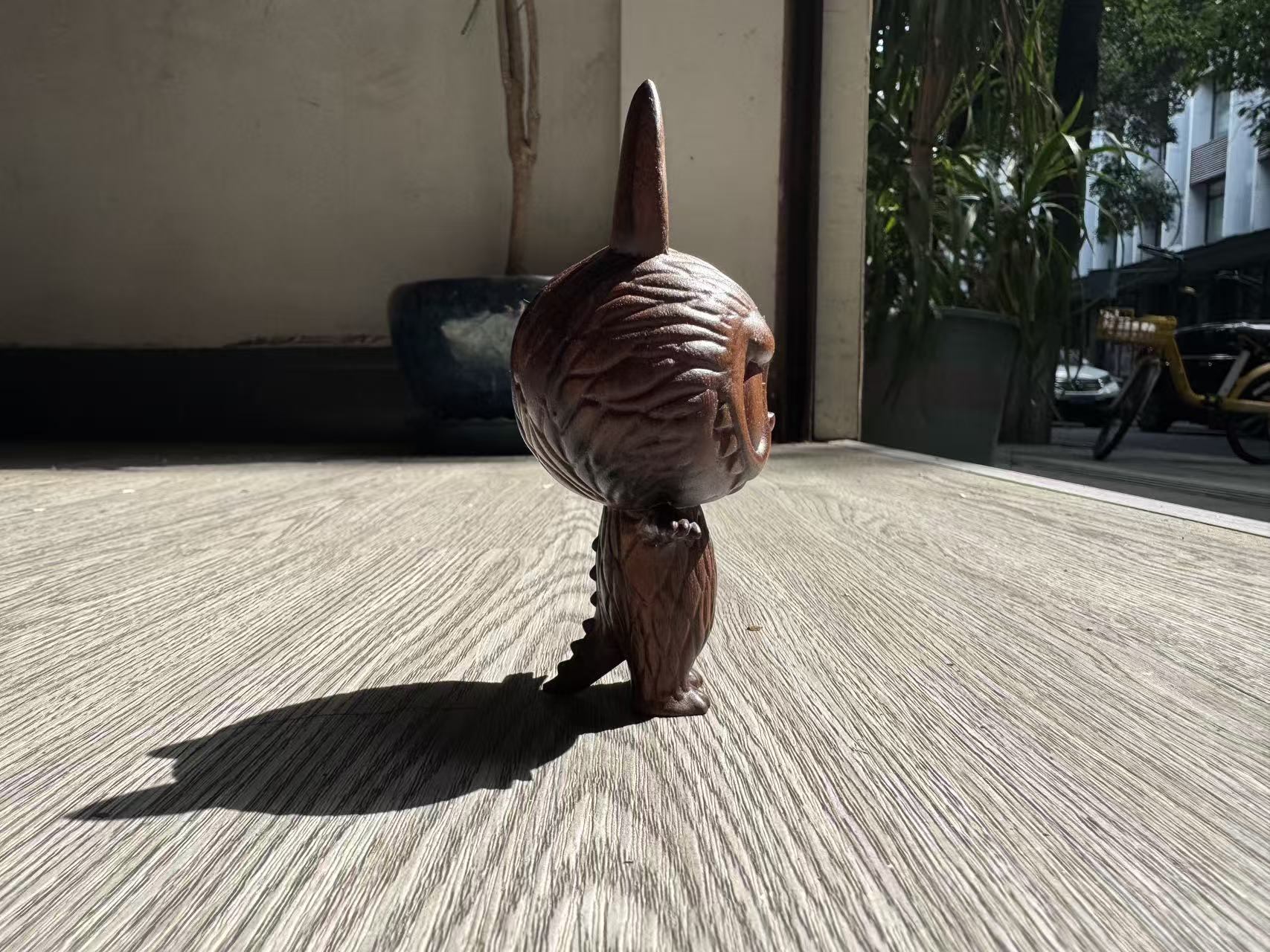 Small brown dog with a large, textured object on its head standing on a concrete surface.