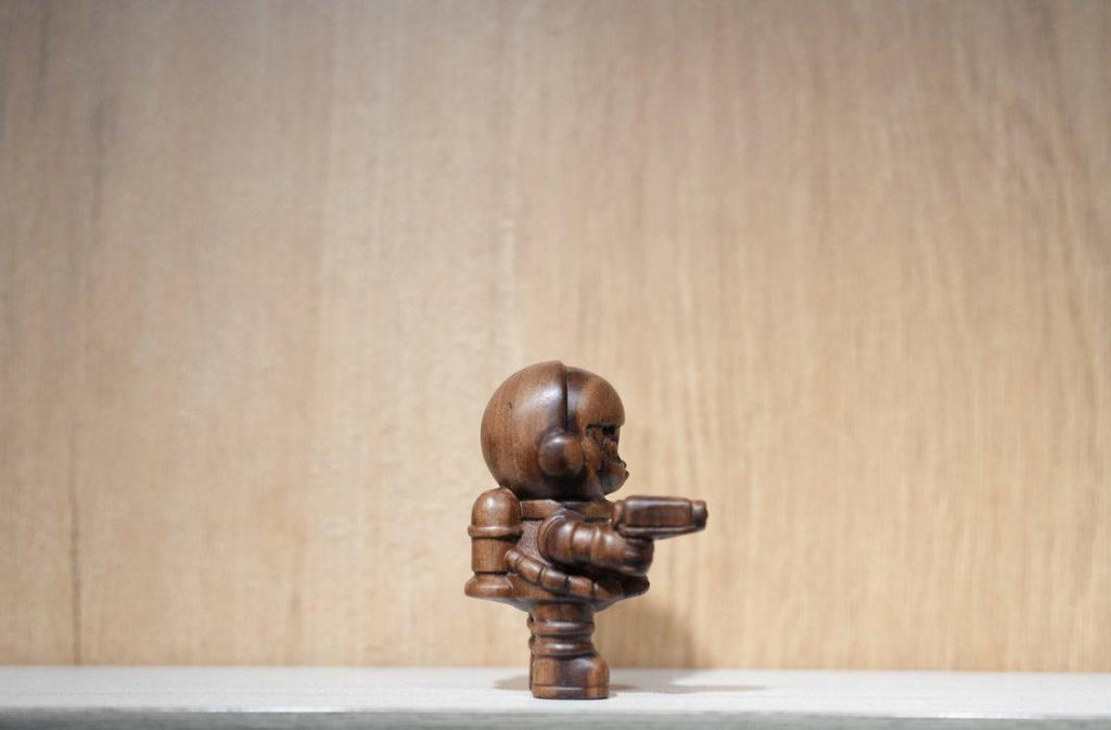 Wooden sculpture of a humanoid figure on a light wooden background
