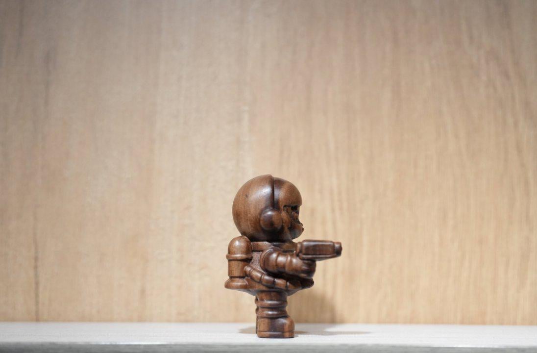 Wooden sculpture of a humanoid figure on a light wooden background