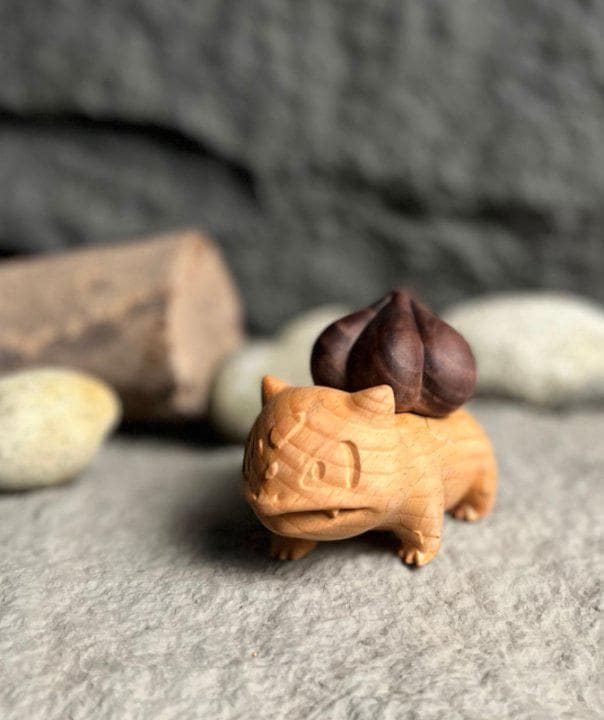 Wooden figurine of a creature with a smaller similar figurine on top