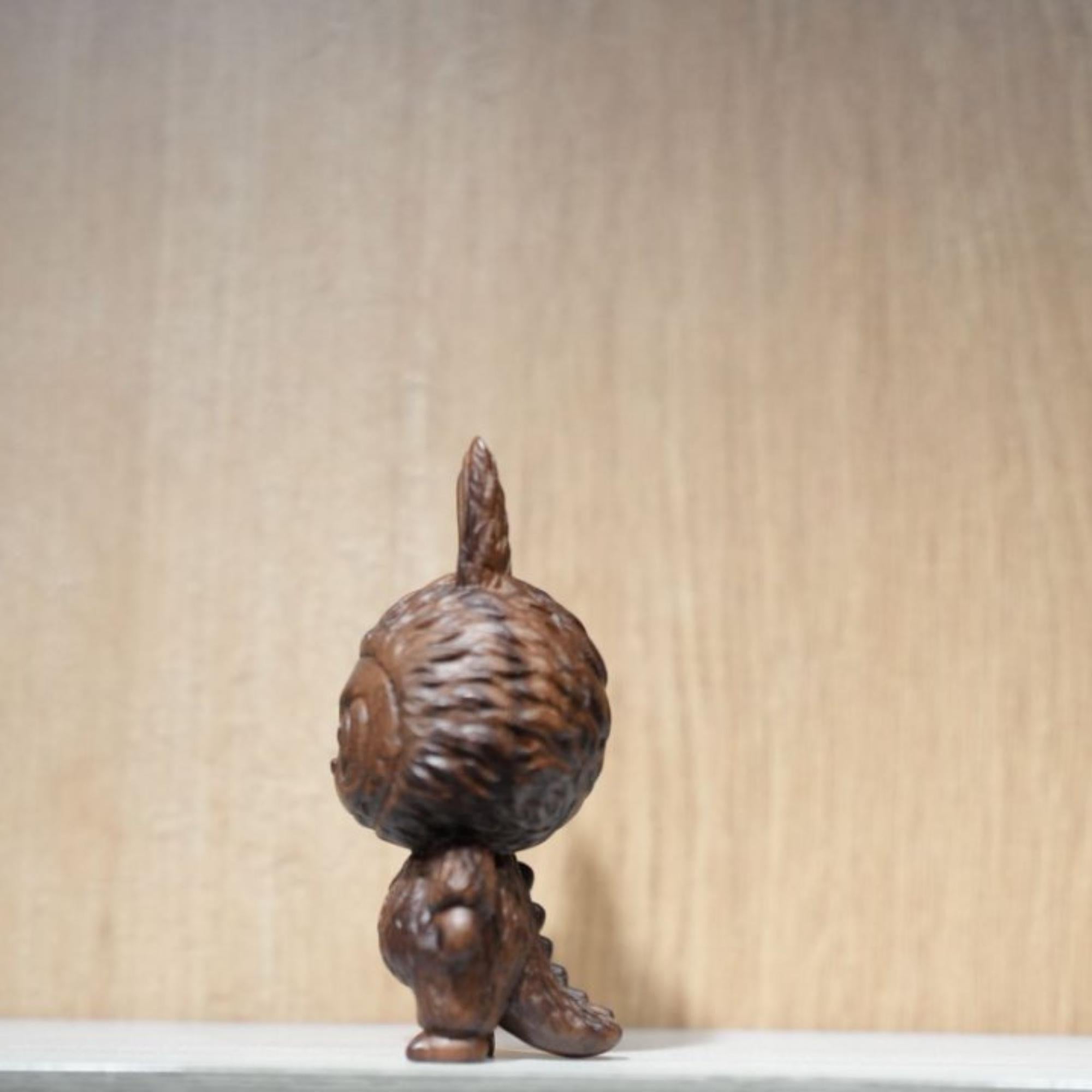Wooden sculpture of a figure with a large head on a plain background