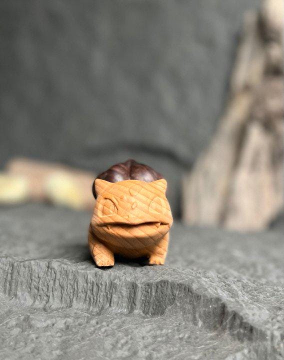 Small figurine of a creature with a brown body and black head on a textured surface.
